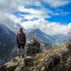 man standing on top of mountain beside cairn stones