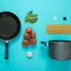 flat lay photography of frying pan beside tomatoes on blue surface